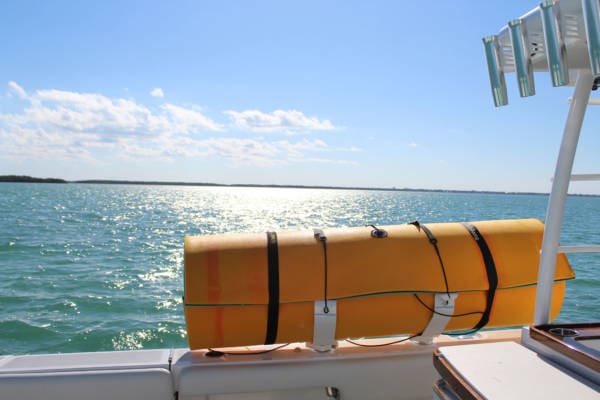 Image of a white FM floating mat storage rack carrying an orange floating mat on the side of a boat in the ocean.