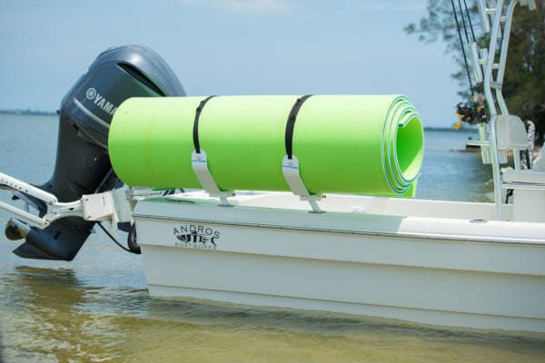 Image of a white FM floating mat storage rack carrying a green and blue floating mat on the back of a boat in the ocean.