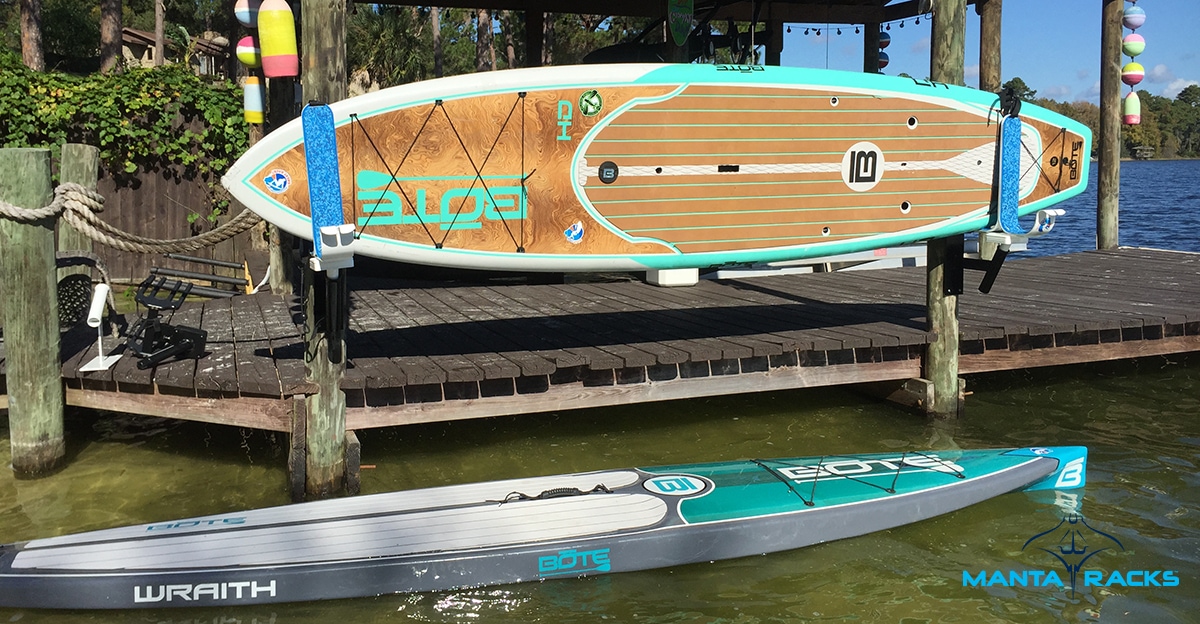 One paddleboard mounted on the dock while the other floats on the water.
