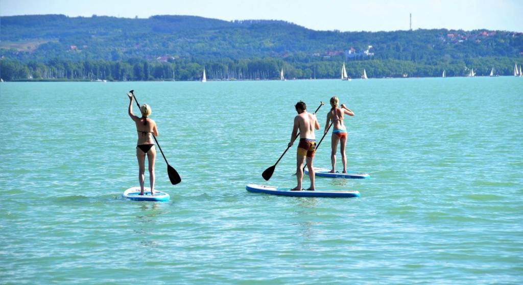 Three women on their paddleboards in open water.