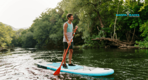 Man standing and paddling on a blue and white SUP.